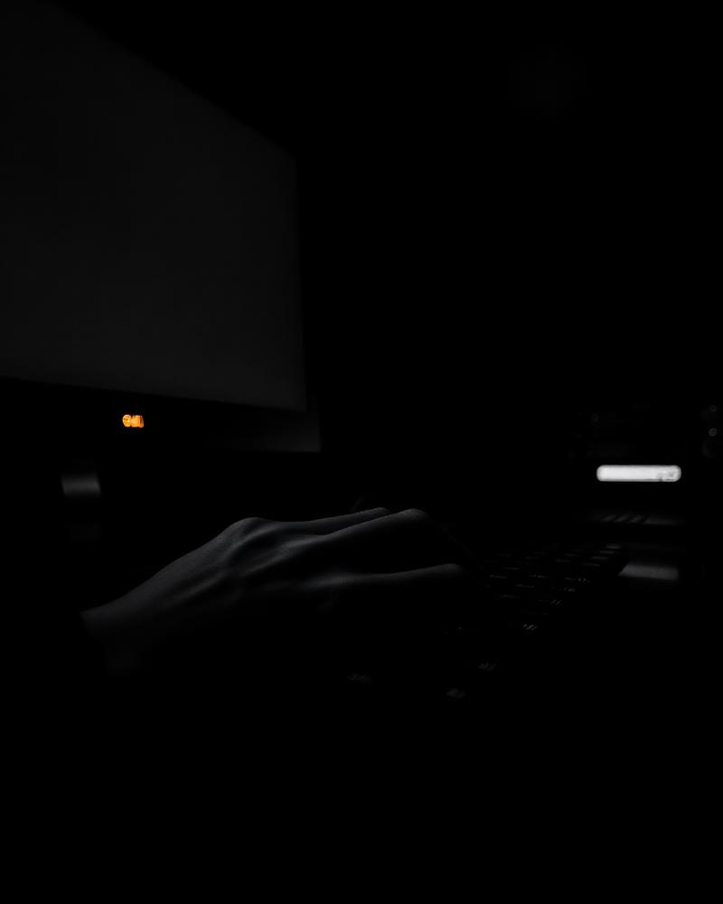 A specialist working a recovery case in a dark room lit by a single orange status light
